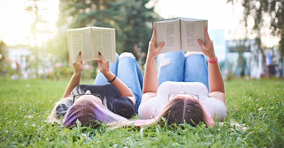 Jugendliche lesen Bücher aus der Wiese